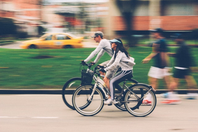 A woman and a man on a bike. Cycling more is one thing you can do to help the planet for Earth Day 2021